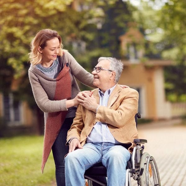 woman walking man in wheelchair